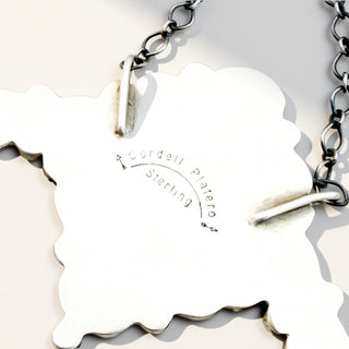 Close-up of a silver necklace with a tag on a white background