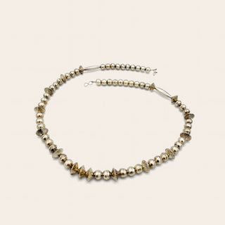 A beaded necklace featuring silver beads, including textured cone-shaped beads and small heart-shaped beads, arranged in a circle on a light beige background.