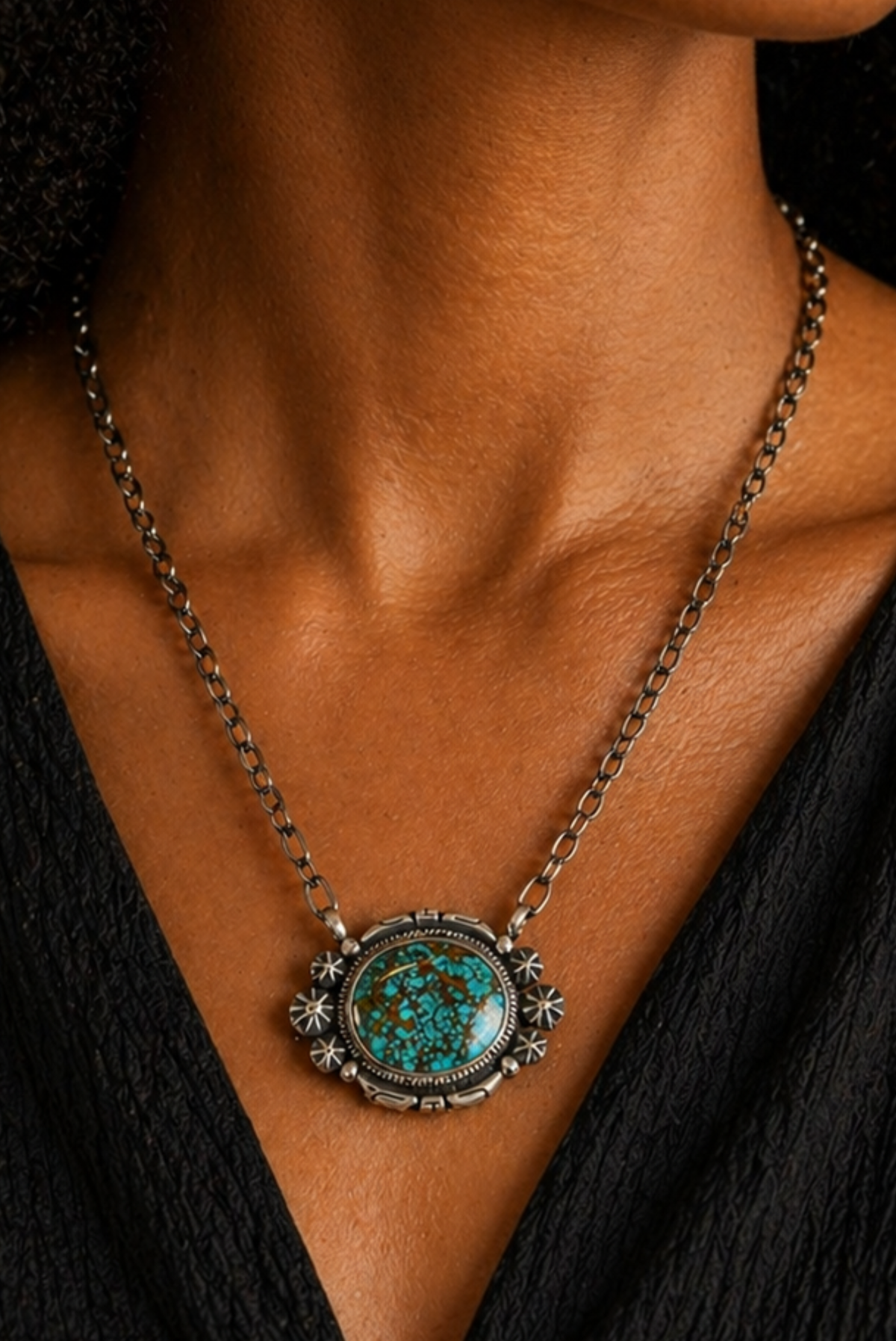 Necklace with a turquoise pendant worn by a person against a black background