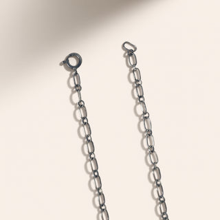 Silver chain necklace on a light beige background