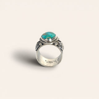 Silver ring with a turquoise stone on a light beige background