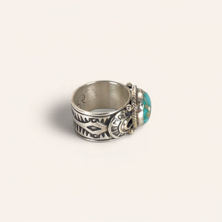 Silver ring with turquoise stone on a light gray background