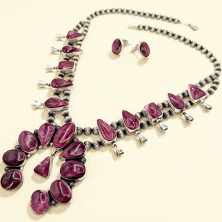 Jewelry set with necklace and earrings featuring purple stones on a beige background