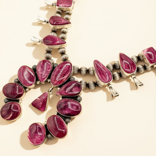 Necklace with purple  gemstones and silver accents on a beige background