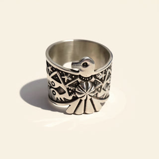 Silver ring with intricate designs on a beige background