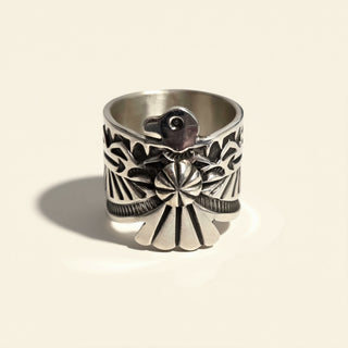 Silver ring with intricate design on a beige background