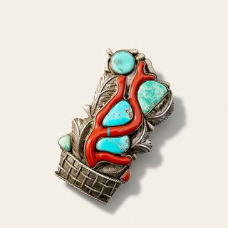 A sterling silver pendant vibrant turquoise and red coral inlay, photographed on a light beige background with a soft drop shadow.
