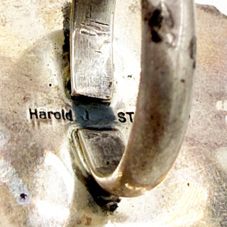 Close-up of a silver ring with engraved text on a textured surface
