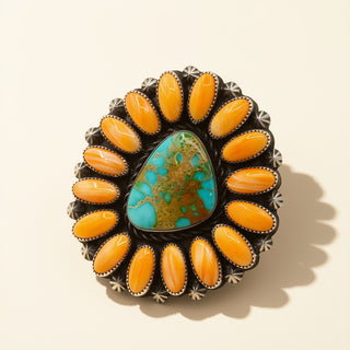Jewelry with orange stones and a central turquoise stone on a beige background