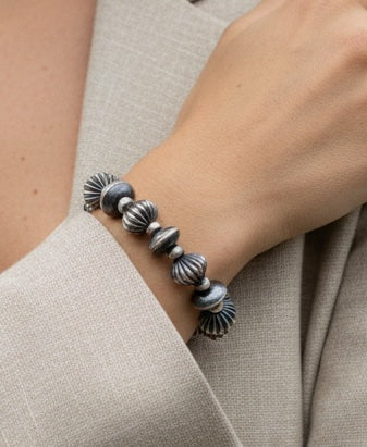 Silver beaded bracelet on a wrist with a neutral background