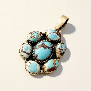 Turquoise stone pendant with silver setting on a beige background