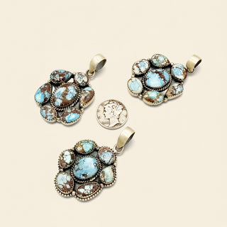 Three ornate pendants with blue gemstones on a beige background