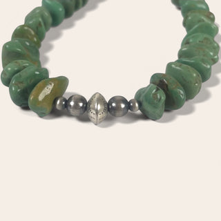 Bracelet with green beads and a silver bead on a white background