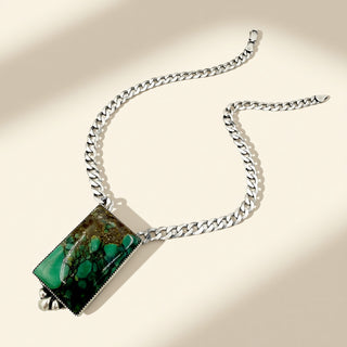 Silver necklace with rectangle green stone on a beige background