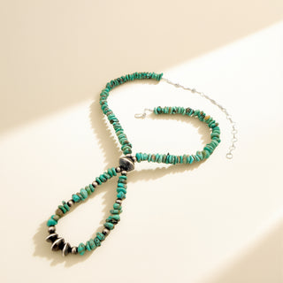 Necklace with turquoise stones and pearls on a beige background