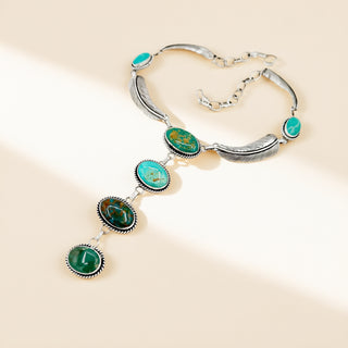 Silver necklace with turquoise stones and feathers on a beige background