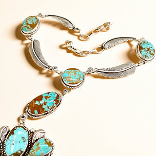 Necklace with turquoise stones and feather designs on a beige background