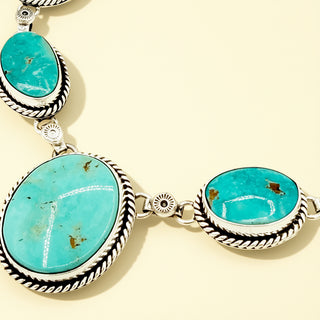 Turquoise stone necklace with silver detailing on a beige background
