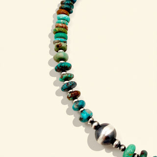 Necklace with turquoise and silver beads on a beige background