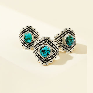 Pair of silver rings with turquoise stones on a beige background