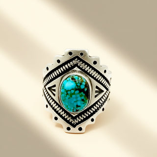 Silver ring with turquoise stone on a beige background