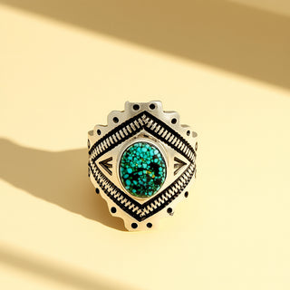 Silver ring with green gemstone on a beige background