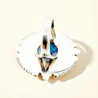 Silver ring with a blue gemstone on a light beige background