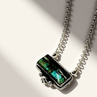 Necklace with a rectangular pendant featuring green and black colors on a light background