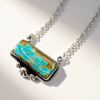 Turquoise stone necklace with silver chain on a light gray background