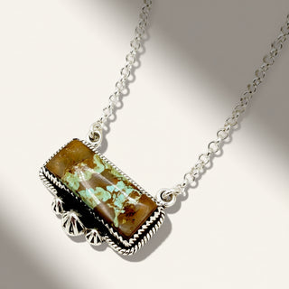 Necklace with a rectangular pendant featuring a natural stone and turquoise stones on a neutral background