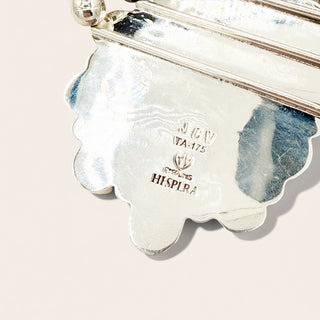 Close-up of a silver object with 'JCV Hespera' branding on a light pink background