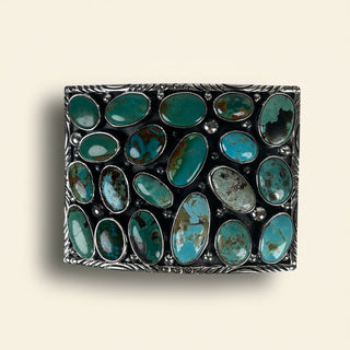 Rectangular metal box with turquoise stones on a beige background