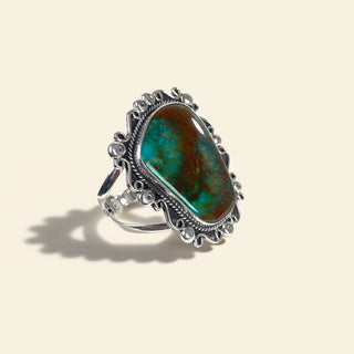Silver ring with a large turquoise stone on a beige background
