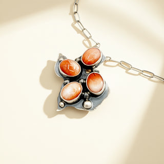 Necklace with orange stone pendant on a beige background