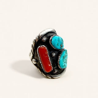 Silver ring with turquoise and red stones on a beige background
