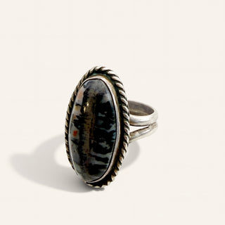 silver ring with black stone on a beige background