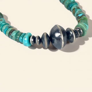 Turquoise beaded necklace on a beige background. 