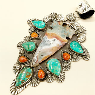 Jewelry piece with turquoise and orange stones on a white background