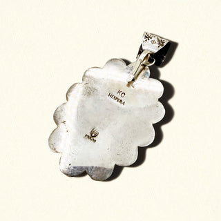 Silver pendant stamp with 'KC Hespera' engraving on a light background