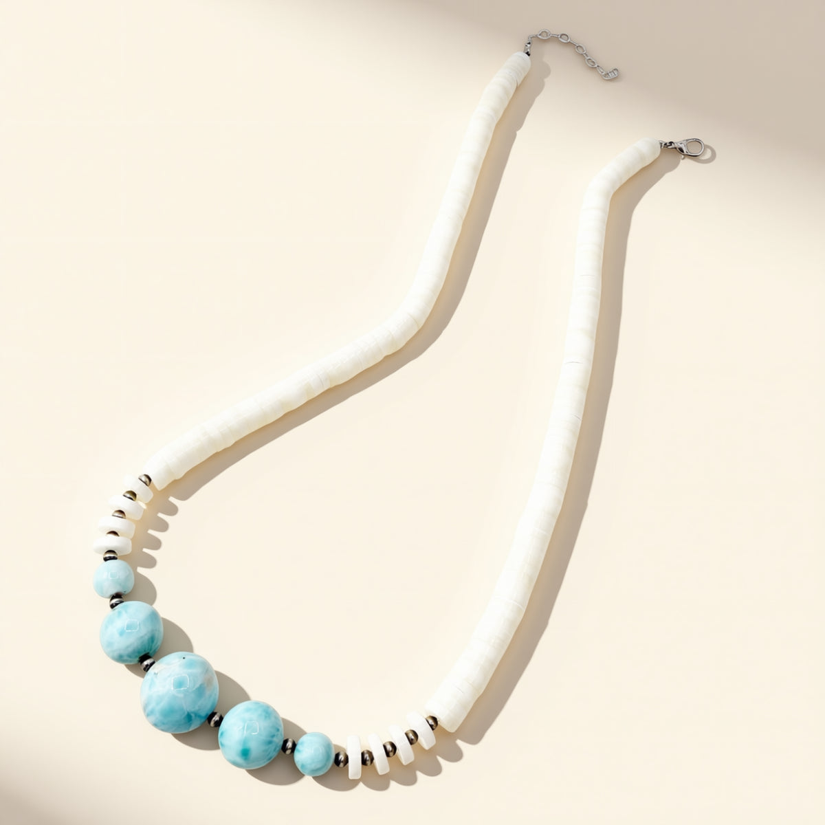 Necklace with white beads and blue accents on a beige background