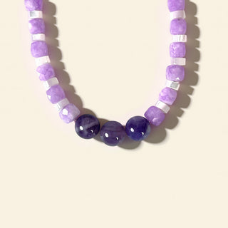 Necklace with purple and white beads on a light beige background