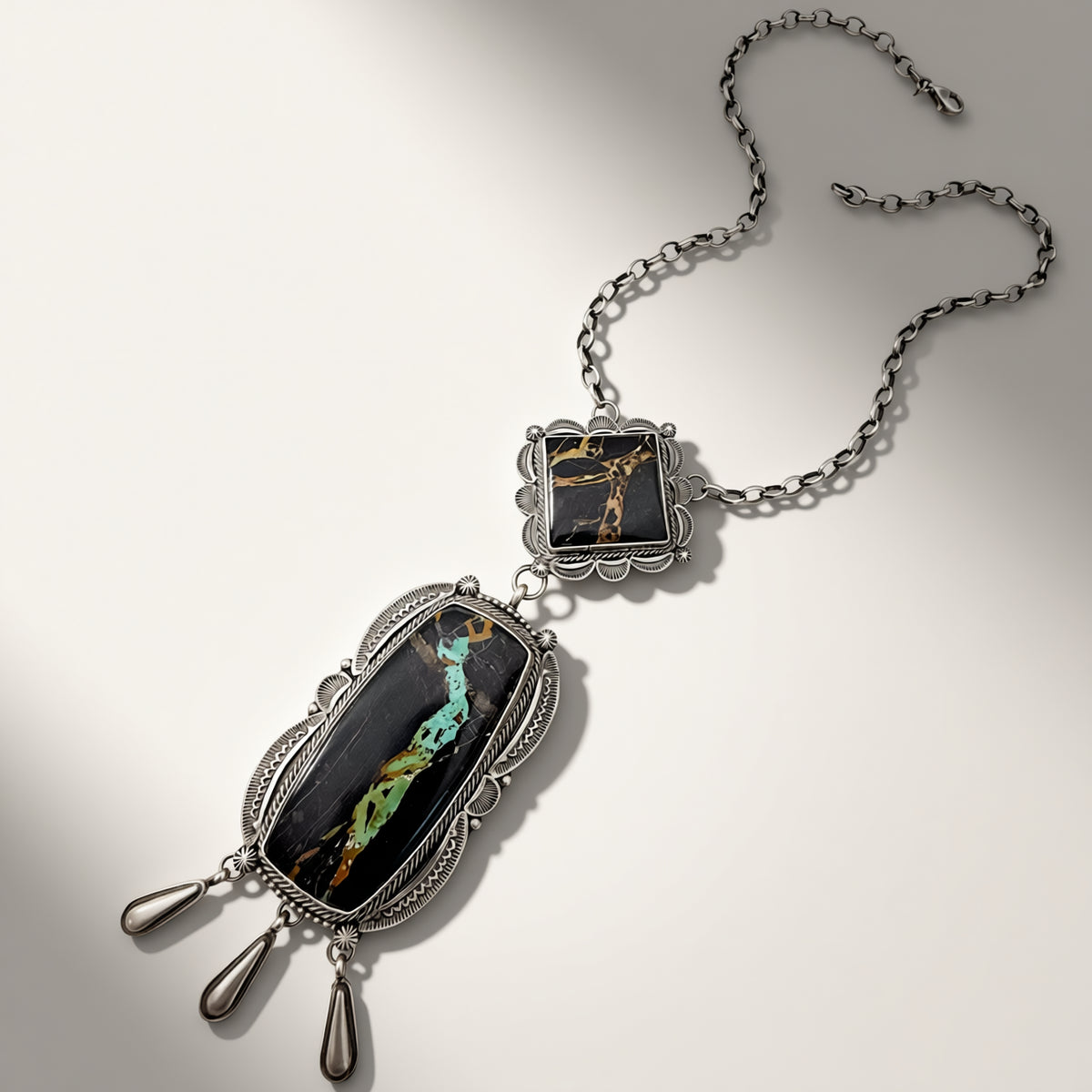 Silver necklace with black and silver pendant on a light gray background