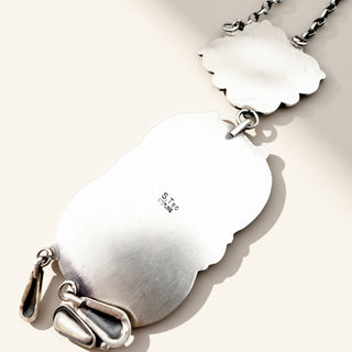 Silver pendant with cloud design on a light background