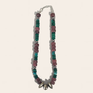 Necklace with multicolored beads and a silver clasp on a light pink background