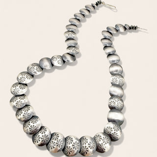Silver beaded necklace on a light beige background
