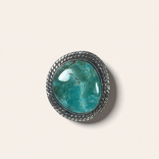 Turquoise stone in a silver frame on a light gray background