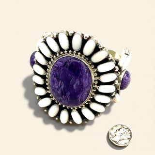 Jewelry cuff with purple stone and white accents on a beige background