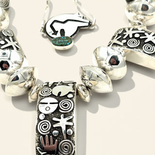 Silver necklace with various pendants on a light background