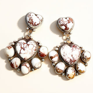Pair of earrings with heart-shaped and round stone designs on a light background
