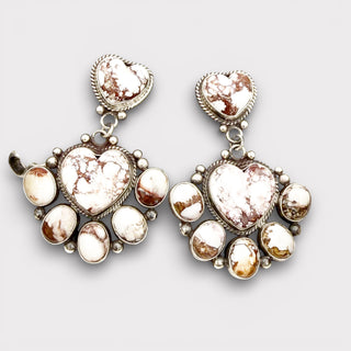Pair of ornate heart-shaped earrings on a light gray background